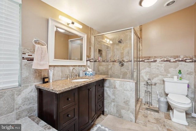 full bathroom with a stall shower, visible vents, toilet, vanity, and tile walls