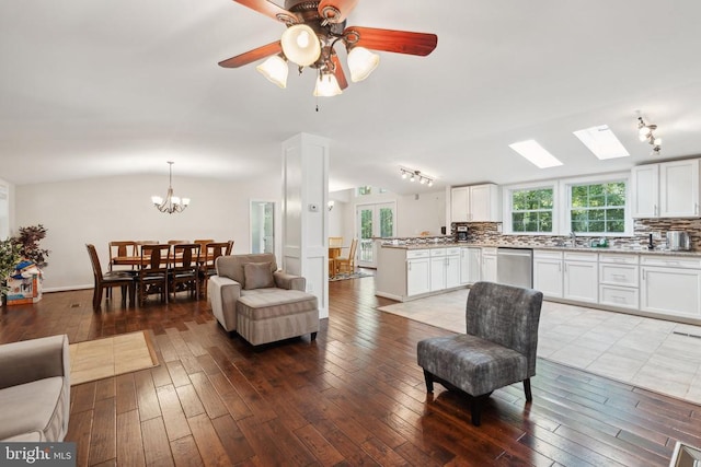 living area with lofted ceiling, ceiling fan with notable chandelier, and wood-type flooring