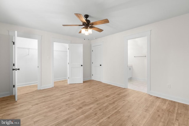 unfurnished bedroom with multiple closets, ensuite bath, light wood-style flooring, and baseboards