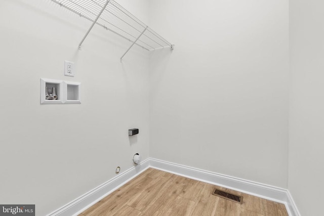 washroom with laundry area, light wood-style flooring, visible vents, and baseboards