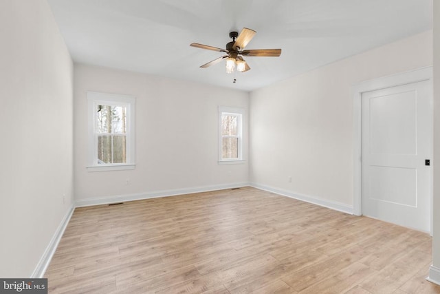 spare room featuring light wood-type flooring, ceiling fan, and baseboards