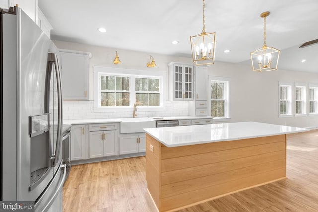 kitchen featuring stainless steel appliances, light countertops, backsplash, light wood-style floors, and a sink