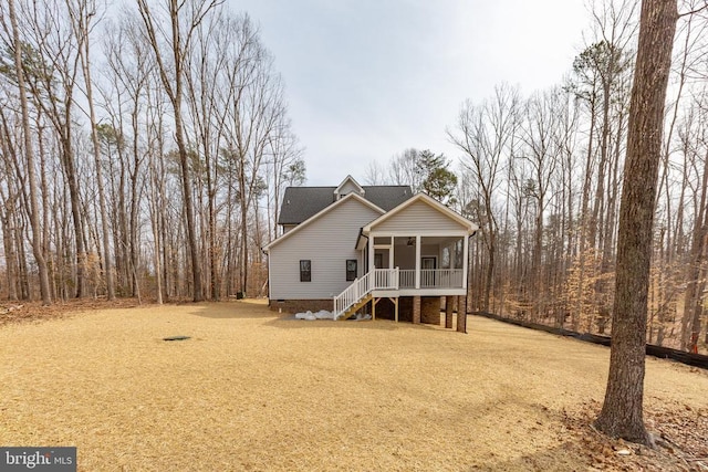 view of front of property with roof with shingles, dirt driveway, a porch, crawl space, and stairs