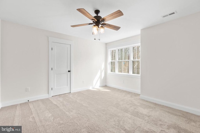 unfurnished room featuring carpet, visible vents, baseboards, and a ceiling fan