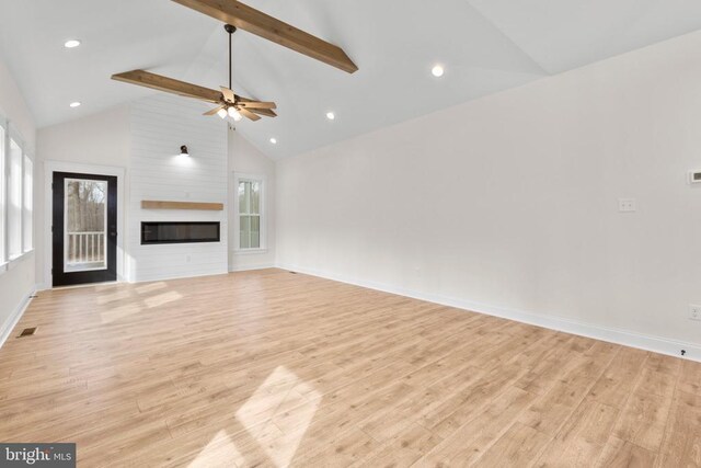 unfurnished living room with a large fireplace, light wood-style flooring, baseboards, and beam ceiling