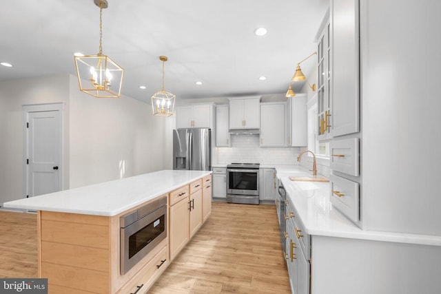 kitchen with tasteful backsplash, a center island, stainless steel appliances, light wood-style floors, and a sink