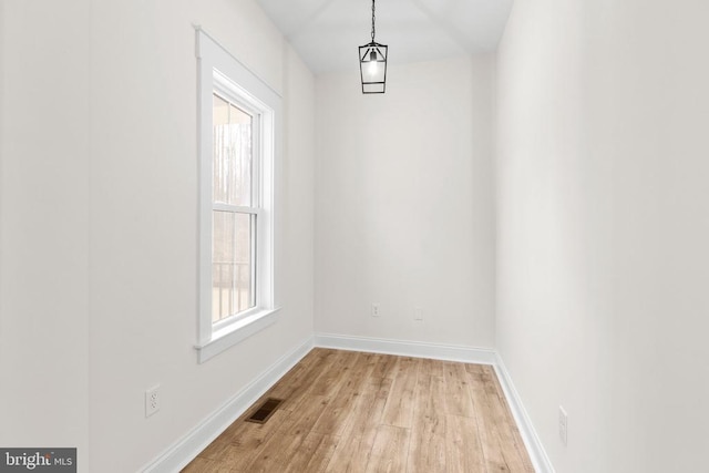 unfurnished dining area with a healthy amount of sunlight, light wood-style flooring, visible vents, and baseboards