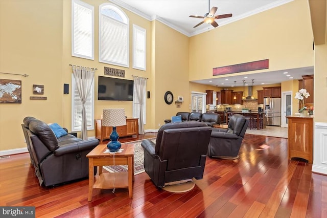 living area featuring dark wood-style floors, a high ceiling, plenty of natural light, and crown molding