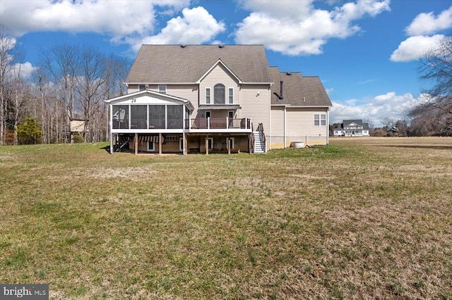 back of property with stairs, a deck, a lawn, and a sunroom