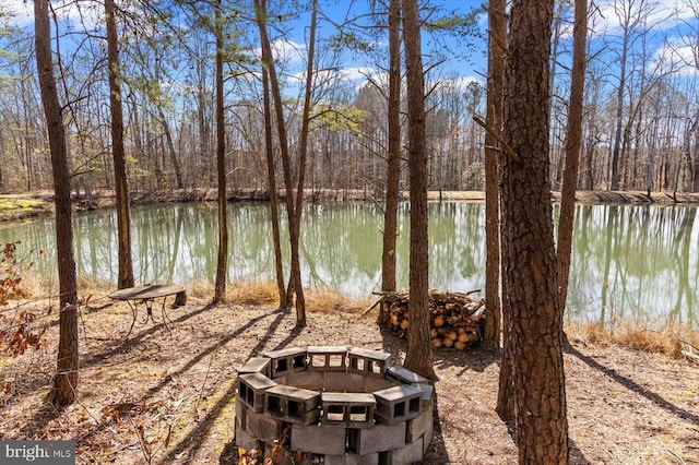 water view with a fire pit and a view of trees