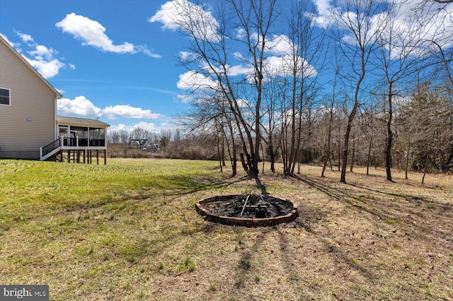 view of yard featuring a sunroom, a fire pit, and stairs