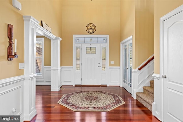 foyer entrance with wainscoting, stairway, ornate columns, and hardwood / wood-style flooring