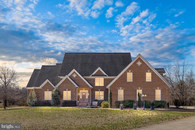 view of front of home with brick siding and a lawn