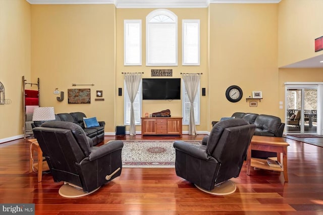 living room with dark wood-type flooring, baseboards, crown molding, and a high ceiling