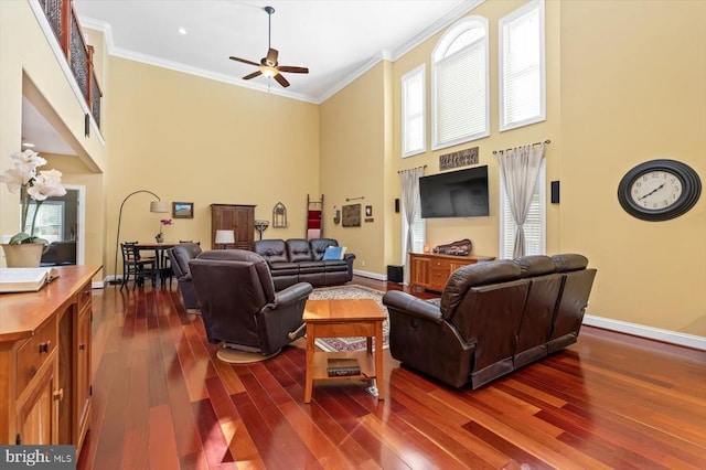 living area with dark wood-style flooring, crown molding, a towering ceiling, and baseboards