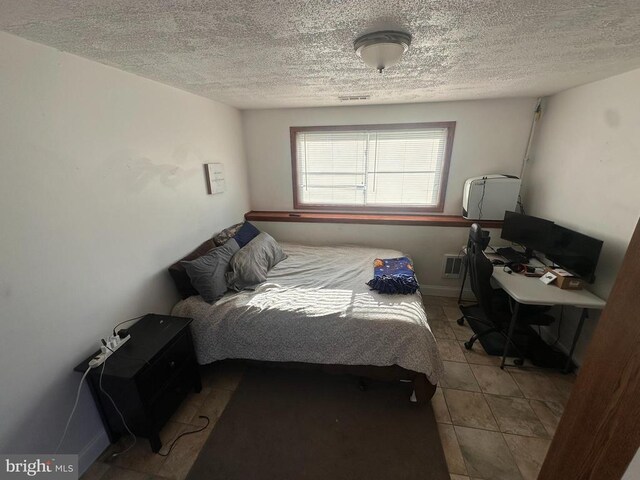 bedroom with light tile patterned floors and a textured ceiling