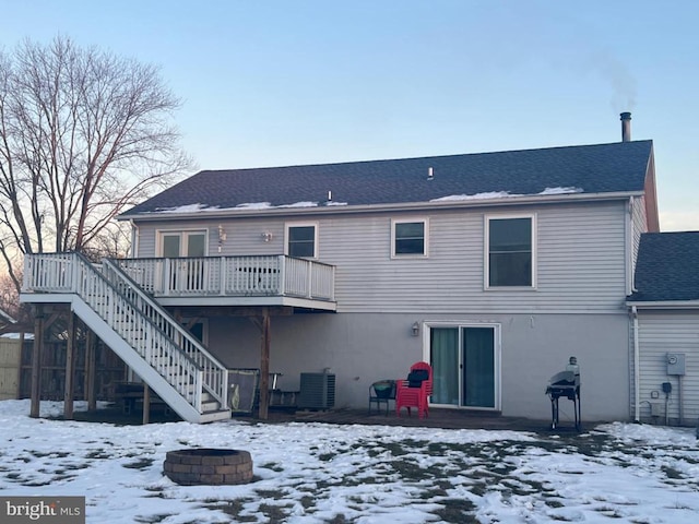 snow covered back of property featuring a wooden deck, an outdoor fire pit, and central AC unit