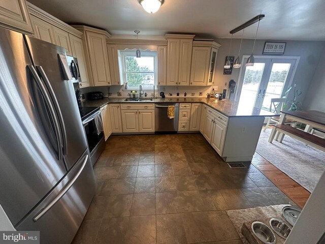 kitchen with pendant lighting, sink, stainless steel appliances, stone countertops, and kitchen peninsula