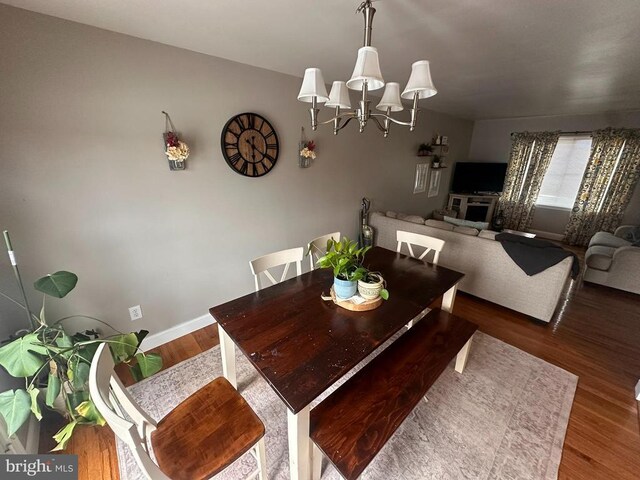 dining room with dark hardwood / wood-style floors and a notable chandelier