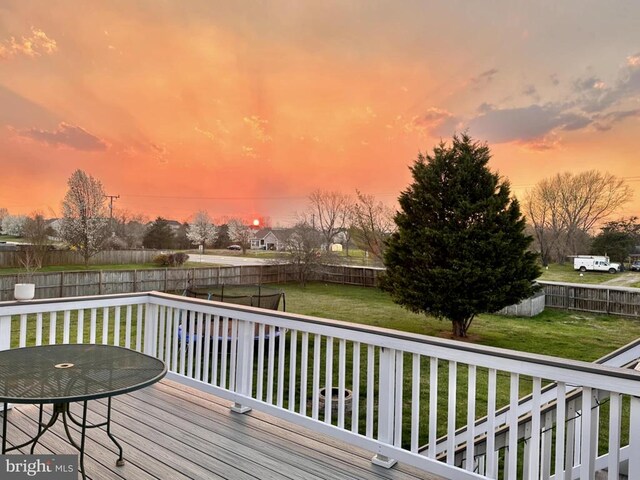 deck at dusk featuring a yard