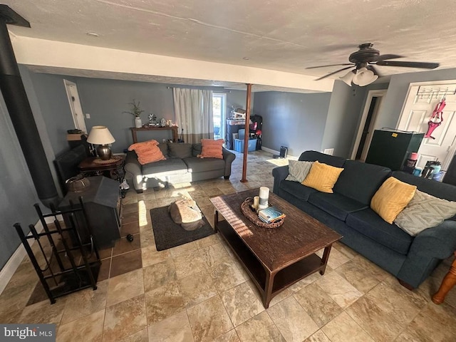 living room with ceiling fan and a wood stove