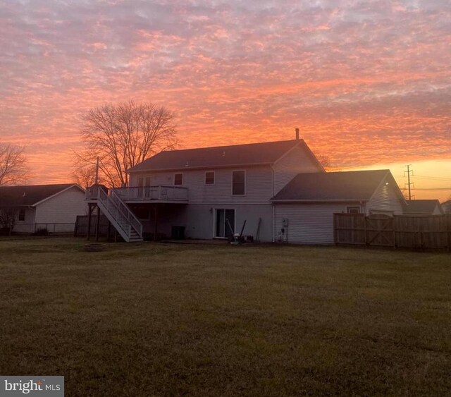 back house at dusk with a deck and a lawn