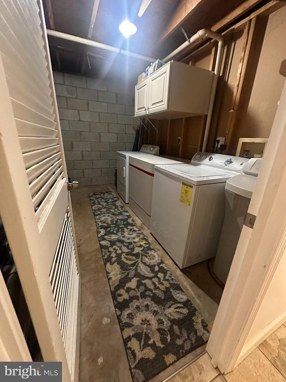 clothes washing area with cabinets and washing machine and clothes dryer