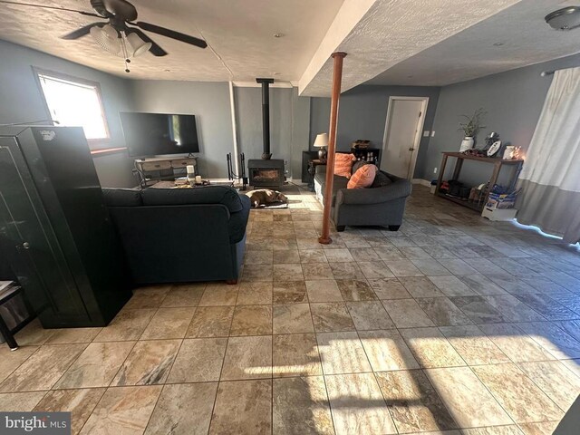 living room featuring a wood stove and ceiling fan