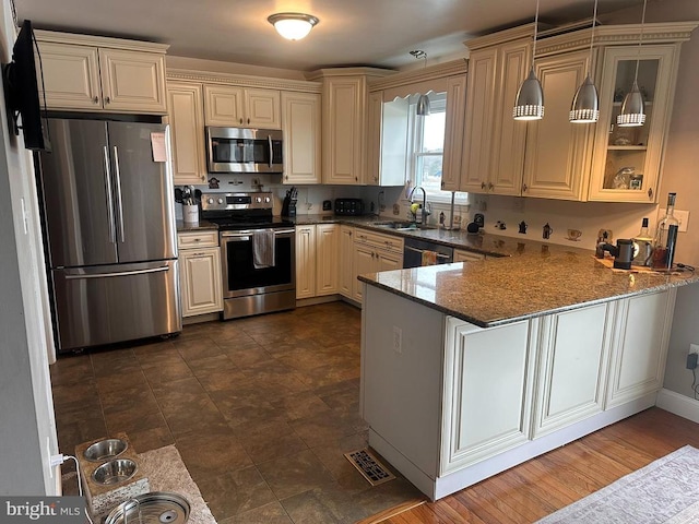 kitchen with sink, hanging light fixtures, dark stone countertops, kitchen peninsula, and stainless steel appliances