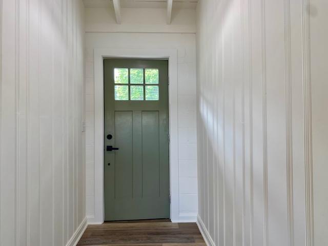 view of exterior entry featuring dark hardwood / wood-style floors and beam ceiling