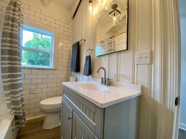 full bathroom featuring hardwood / wood-style floors, toilet, shower / tub combo with curtain, and vanity