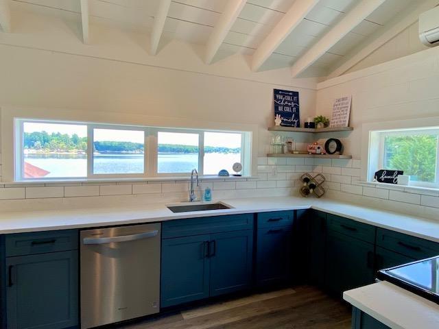 kitchen with sink, backsplash, a water view, lofted ceiling with beams, and stainless steel dishwasher