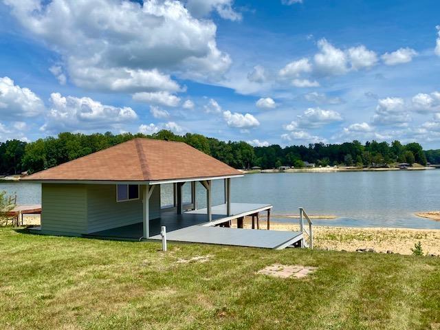 view of dock with a water view and a lawn