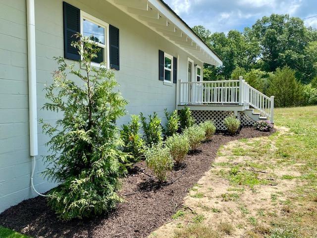 view of side of property with a deck and a lawn