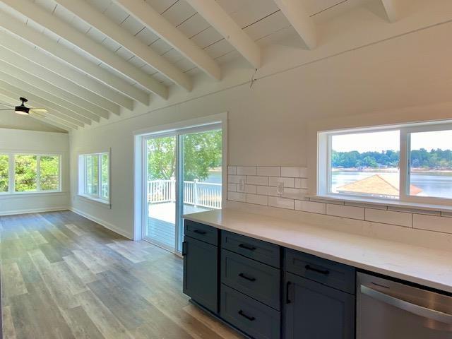 kitchen with light hardwood / wood-style flooring, vaulted ceiling with beams, backsplash, and stainless steel dishwasher