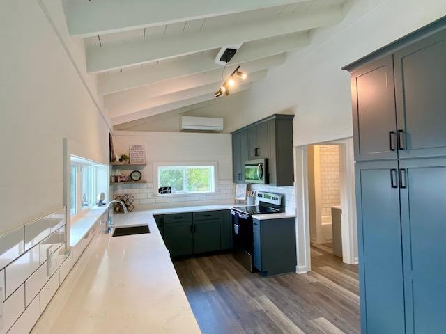 kitchen featuring appliances with stainless steel finishes, dark wood-type flooring, an AC wall unit, decorative backsplash, and sink