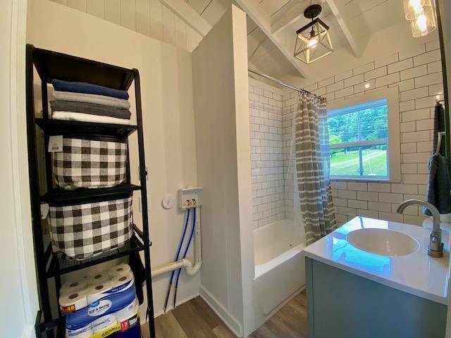 bathroom with hardwood / wood-style flooring, shower / bathtub combination with curtain, and vanity