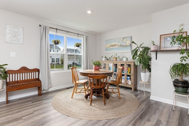 dining space featuring baseboards, wood finished floors, and recessed lighting