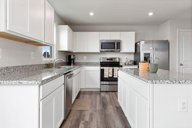 kitchen featuring dark wood finished floors, stainless steel appliances, a sink, a kitchen island, and white cabinetry