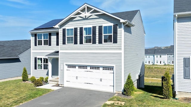 view of front facade featuring a garage, solar panels, a front lawn, and aphalt driveway