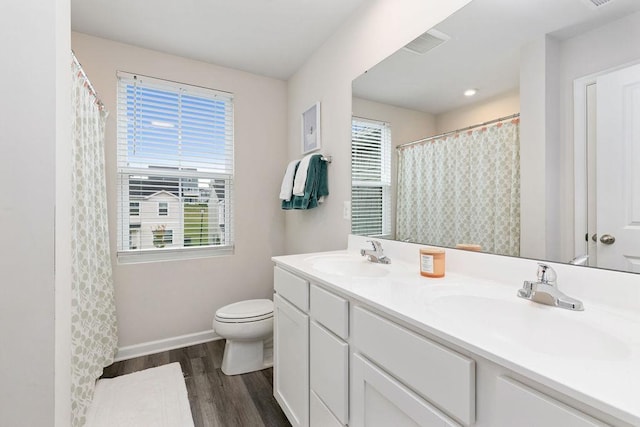 bathroom featuring wood finished floors, a sink, double vanity, and toilet