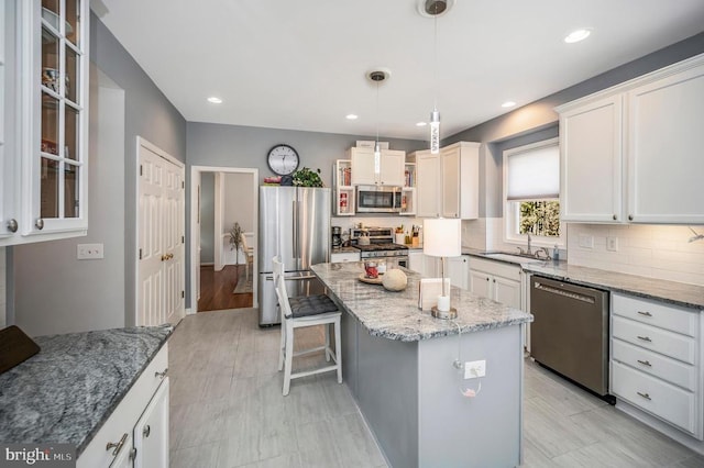 kitchen featuring a center island, stainless steel appliances, tasteful backsplash, light stone countertops, and a kitchen breakfast bar