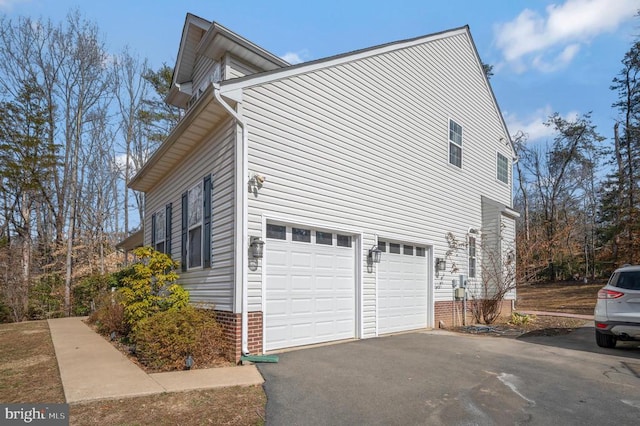 view of side of property featuring driveway, a garage, and brick siding