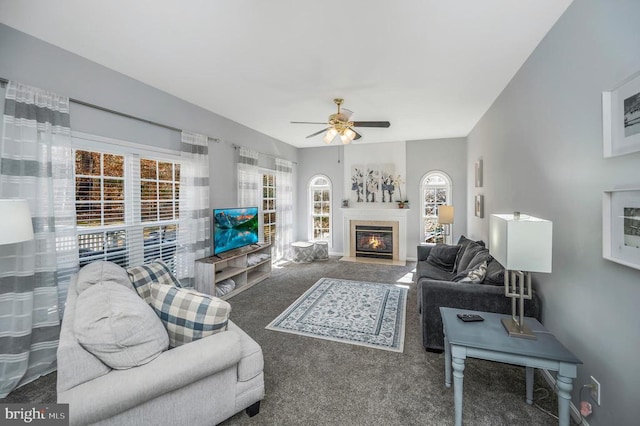 carpeted living area with a glass covered fireplace and ceiling fan