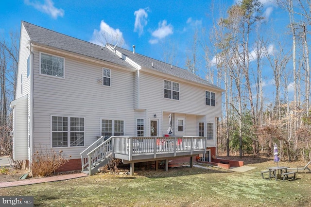 back of house with a shingled roof, a lawn, and a wooden deck