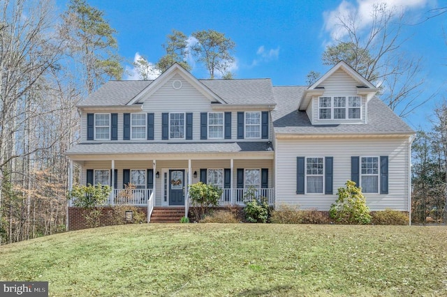 colonial house with covered porch, a shingled roof, and a front yard