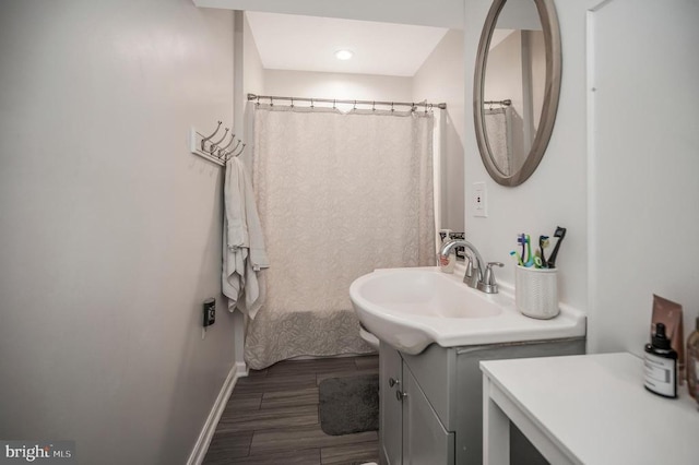 bathroom with wood finish floors, vanity, and baseboards