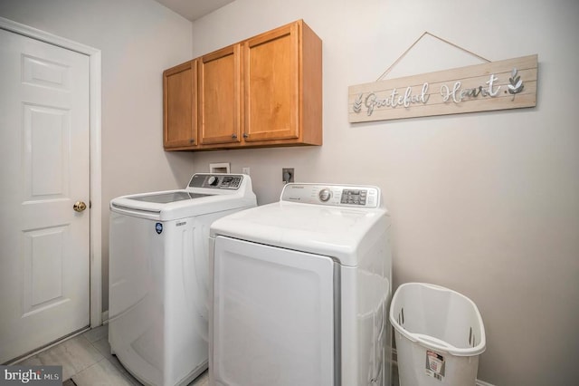 laundry area featuring light tile patterned floors, separate washer and dryer, and cabinet space