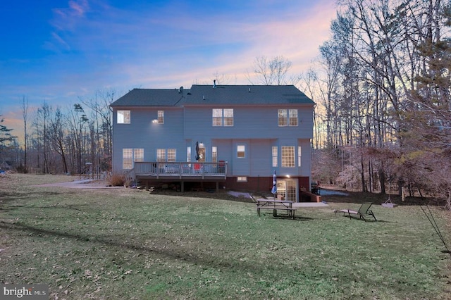 back of property at dusk featuring a lawn and a wooden deck