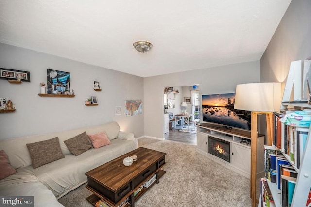 carpeted living area with a glass covered fireplace and baseboards